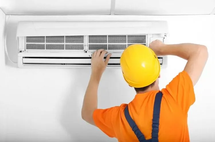 Technician performing AC maintenance, following an AC maintenance checklist to ensure efficient cooling and system longevity